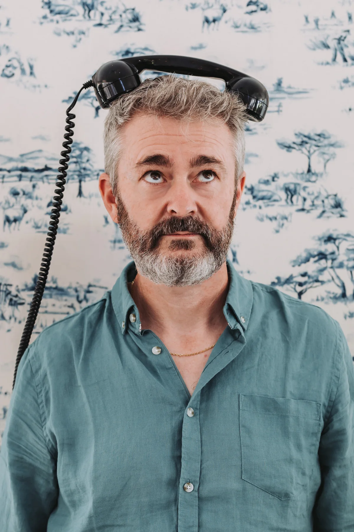 David Huitorel, le combiné d'un vieux téléphone posé sur la tête, les yeux levés au ciel
